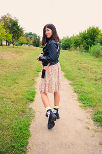 Full length portrait from the back of a young black-haired girl who is walking along a footpath