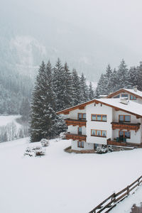 Snow covered house and trees against sky