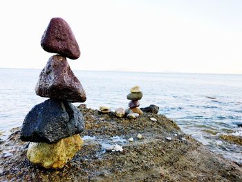 Stack of stones on beach against sky