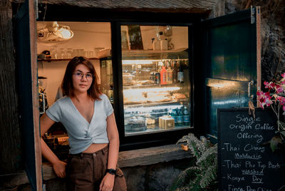 Portrait of smiling woman standing by window