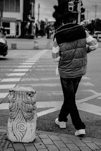 Rear view of man walking on sidewalk