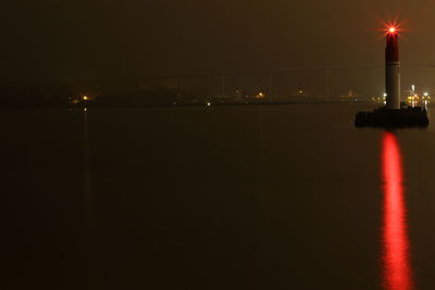 Illuminated sea against clear sky at night