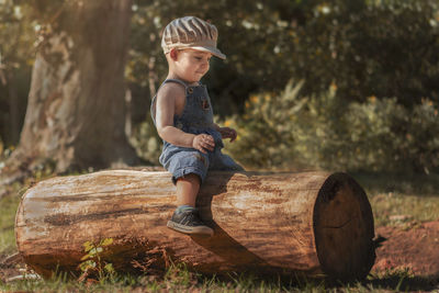 Full length of boy sitting on log