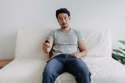 Man watching tv while sitting on bed at home