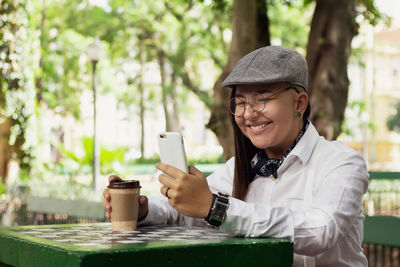 Young woman using mobile phone while sitting on table