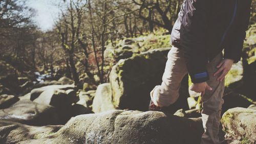 Low section of man standing by tree in forest