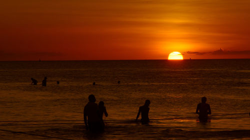 Silhouette people in sea during sunset