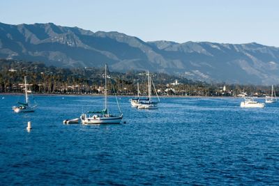 Boats sailing in sea against clear sky