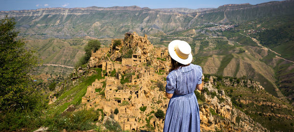 Rear view of woman standing on landscape against mountain