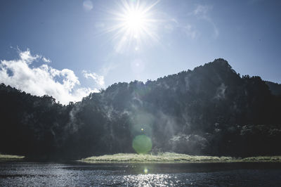 Sunlight streaming through lake against sky on sunny day