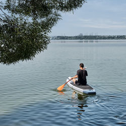Man rowing boat in lake against trees