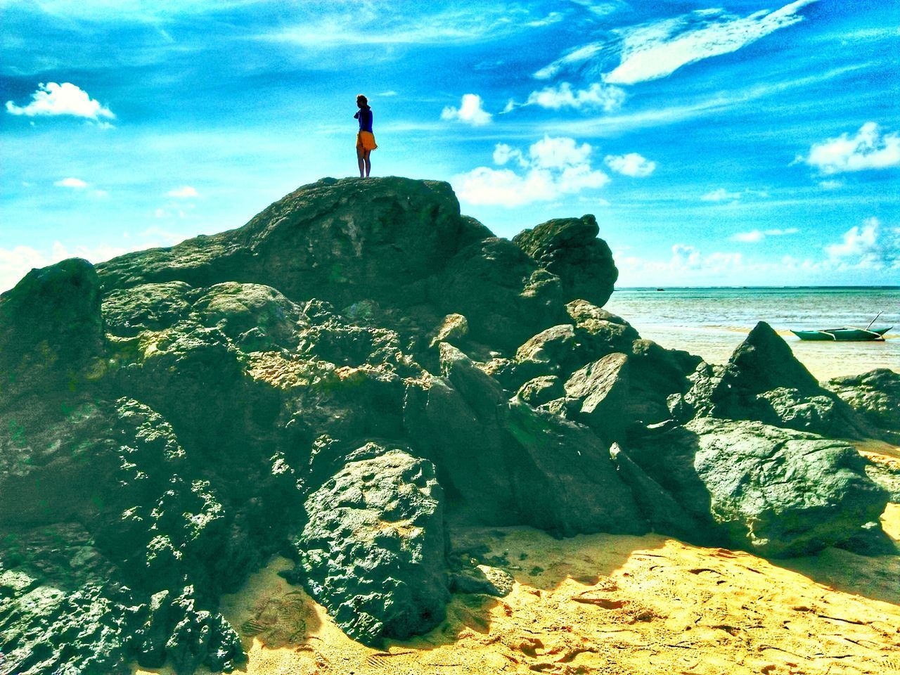 MAN STANDING ON CLIFF BY SEA