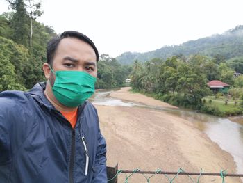 Portrait of young man standing against trees