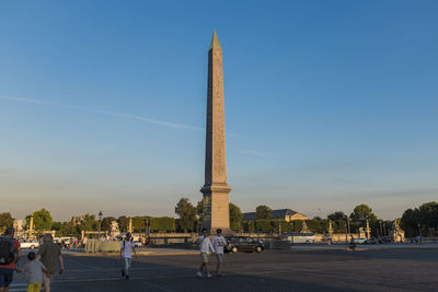 People at luxor obelisk in place de la concorde against sky
