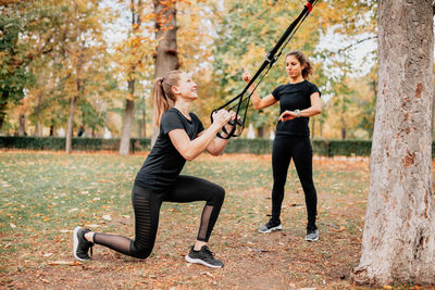 Friends exercising by trees in park during autumn