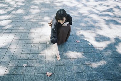 High angle view of woman sitting on footpath