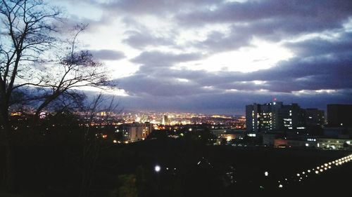 Illuminated cityscape against cloudy sky