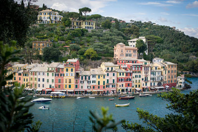 Houses by river in city against sky