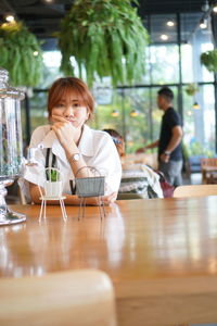 Portrait of young woman sitting at restaurant table