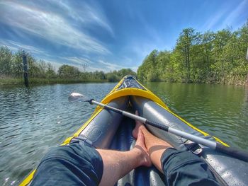 Low section of person in boat on lake against sky