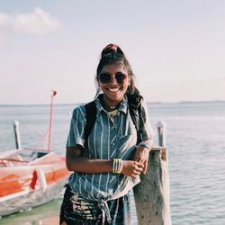Portrait of smiling man standing by sea against sky