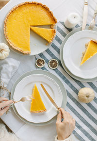 Cropped hands of woman having cake in plate on table