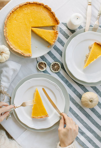 Cropped hands of woman having cake in plate on table