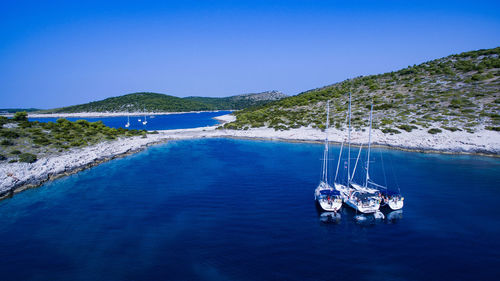 High angle view of boats sailing in sea against clear blue sky