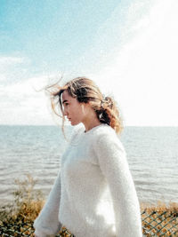 Side view of woman standing at beach against sky