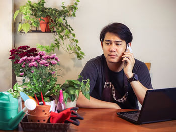 Young man using mobile phone while sitting on table