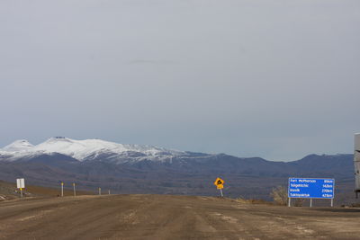 Road by snowcapped mountain against sky