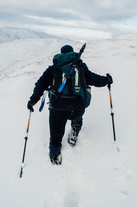 Rear view of hiker on snow covered landscape