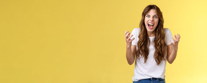 Young woman standing against yellow background