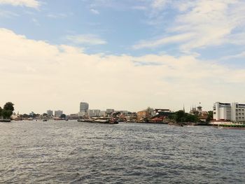 Sea by buildings against sky in city
