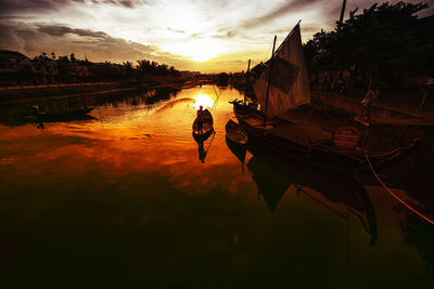 Boats in river at sunset