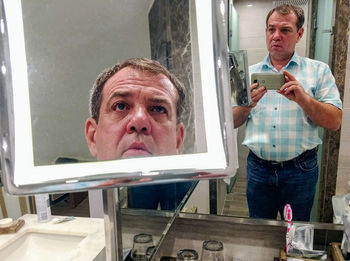 Man taking mirror selfie in bathroom