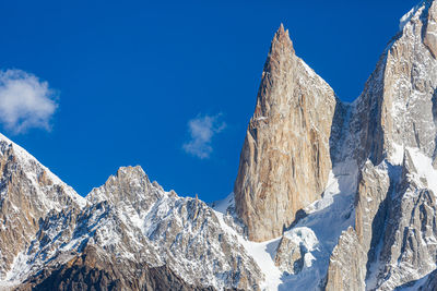 Low angle view of snowcapped mountains against blue sky