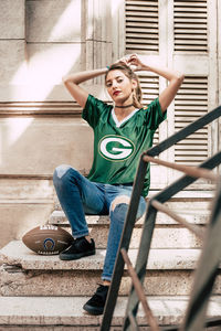 Young woman looking down while sitting on railing