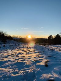 Scenic view of snow covered field against sky during sunset