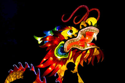 Low angle view of multi colored woman against black background