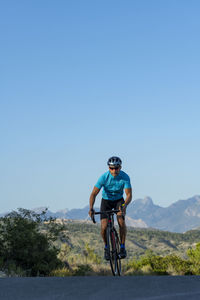 A man, standing up on his pedals, bikes uphill in costa blanca