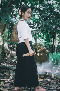 Young woman standing on rock against trees