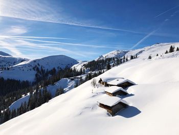 Scenic view of snow covered mountains against blue sky