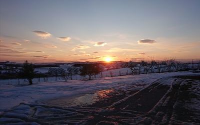 Scenic view of snow covered land during sunset