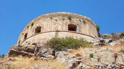 Low angle view of old ruin building against blue sky