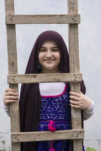 Portrait of smiling girl looking through ladder