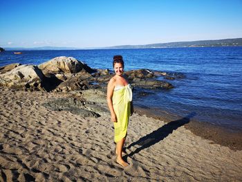 Portrait of woman standing on beach against sky