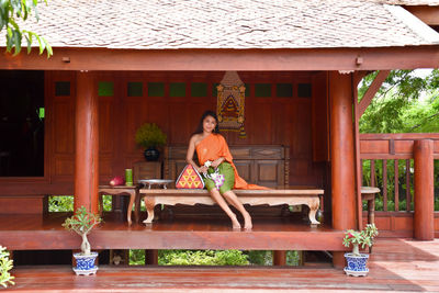 Portrait of woman sitting on seat against building