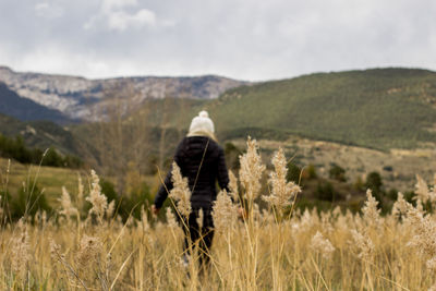 Rear view of woman walking on field