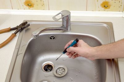 High angle view of hand holding screwdriver over sink